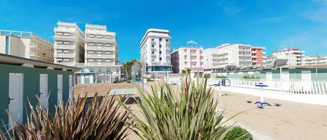 A beachfront hotel with multiple buildings, a sandy beach, and a clear blue sky.