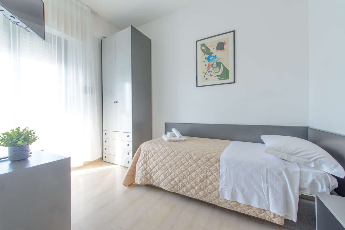 A modern bedroom with a bed, a bedside table, a potted plant, and a wardrobe.
