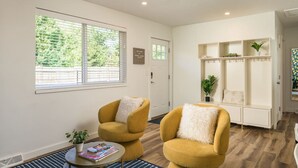 A modern living room with two mustard-colored armchairs, a small round table with a magazine, and a bookshelf with decorative items. - Central, Arcade table, 5 mins to Downtown Denver (Denver)