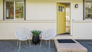 A building with a yellow door, two white chairs, and a potted plant in front. - Central, Arcade table, 5 mins to Downtown Denver (Denver)