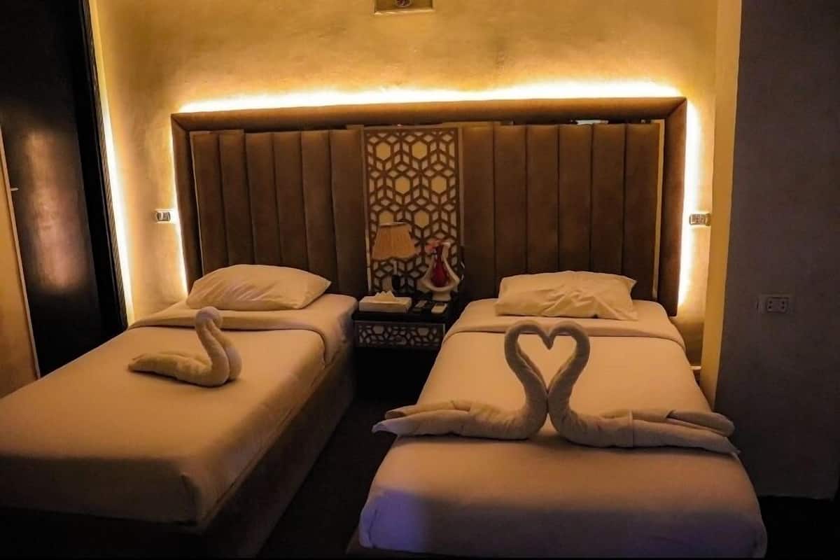 A hotel room with two beds, each with a swan-shaped towel arrangement.