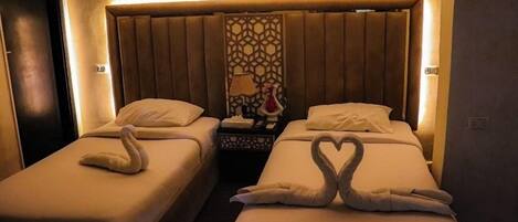 A hotel room with two beds, each with a swan-shaped towel arrangement.
