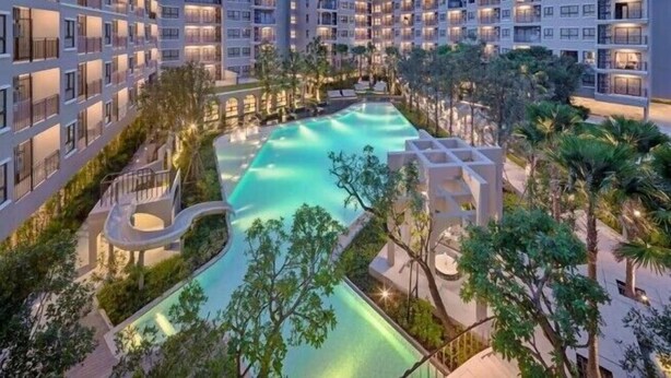 A modern hotel with multiple floors, a central swimming pool, and surrounding greenery. - La Casita Hua Hin (Hua Hin)
