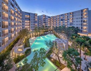 A modern hotel with multiple floors, a central swimming pool, and surrounding greenery. - La Casita Hua Hin (Hua Hin)