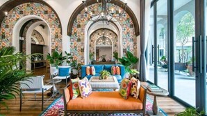 A spacious living area with a sofa, coffee table, and chairs, surrounded by large windows and a colorful tiled wall. - La Casita Hua Hin (Hua Hin)