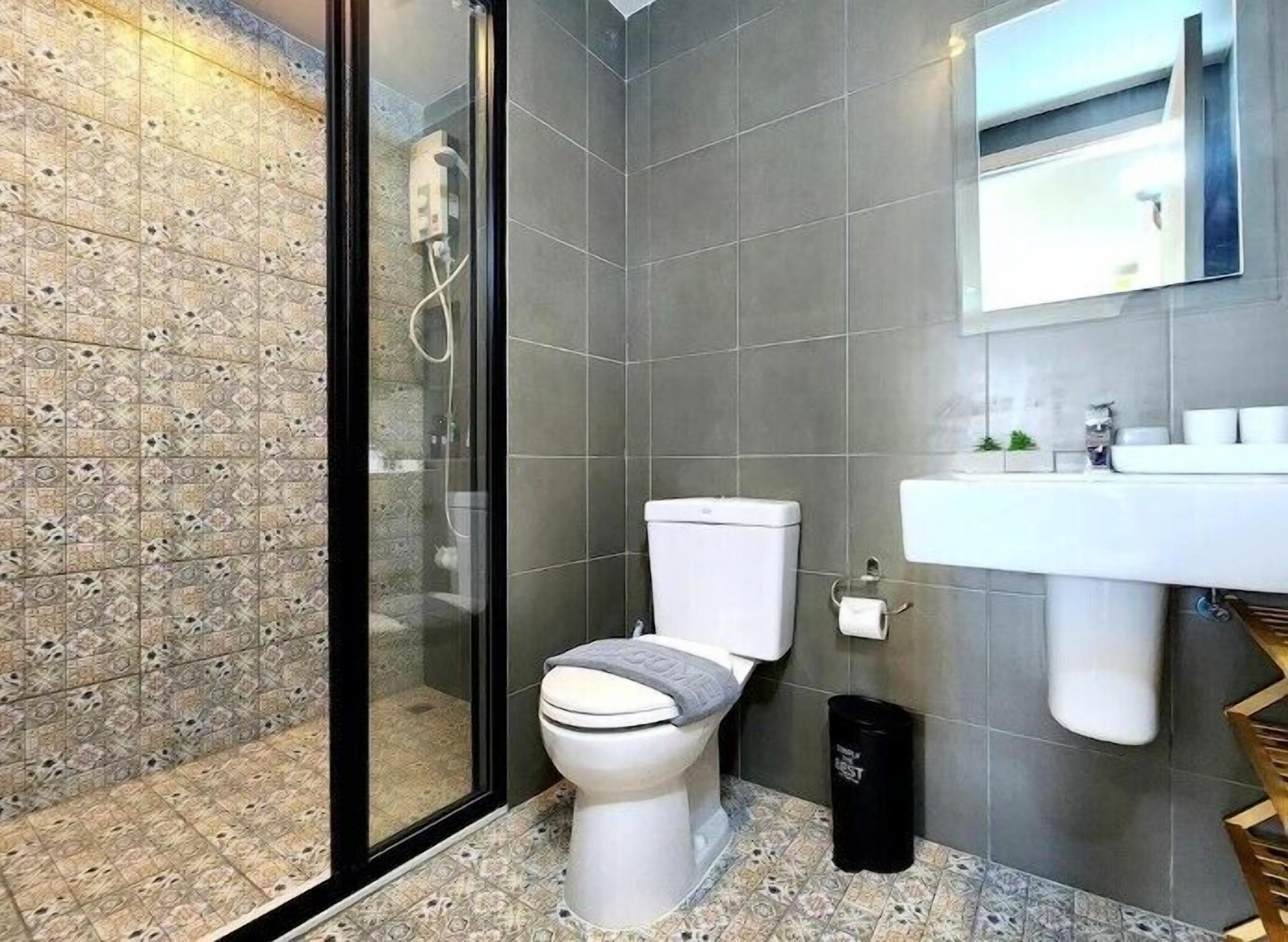 A modern bathroom with a toilet, shower, and sink.