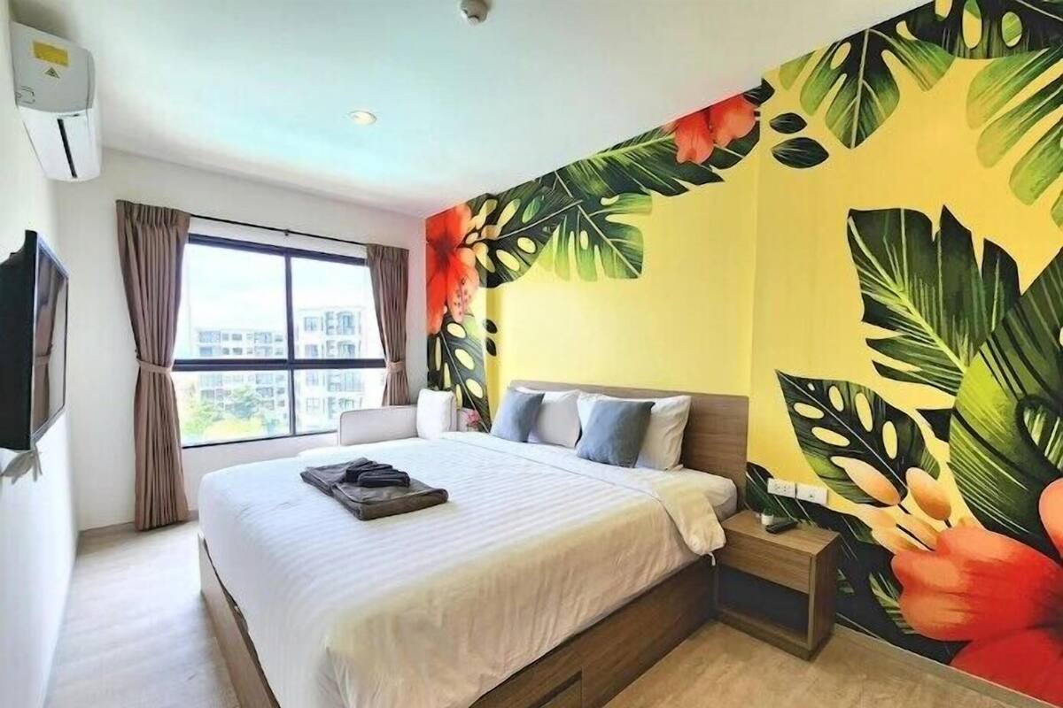 Camera d'albergo con un letto grande, un comodino, una televisione e una finestra con tende.