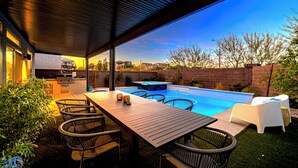 An outdoor patio with a pool, a dining table, and chairs. - Cozy Modern 5bd Home, 10mins to Airport, 15mins to the Strip, Pool & Jacuzzi! (Las Vegas)