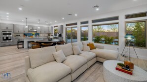 A modern kitchen with a dining area, a large sofa, and a round coffee table. - Cozy Modern 5bd Home, 10mins to Airport, 15mins to the Strip, Pool & Jacuzzi! (Las Vegas)