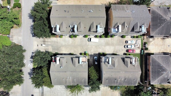 An aerial view of a residential area with multiple houses, a parking lot, and a road. - Lux Galleria Home-5BR Roof Deck (Houston)