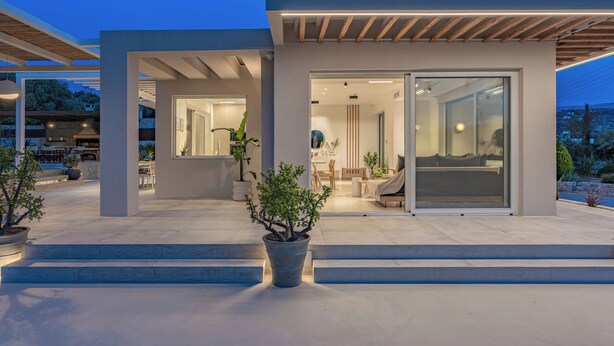 A modern house with a patio, a dining area, and a living room with a large sliding glass door.