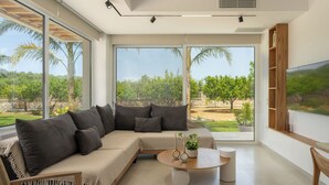 A modern living room with a sectional sofa, a round coffee table, and a large TV on the wall.