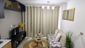 A living room with a sofa, a coffee table, a TV, and a curtain. - Alojamiento en San Diego 376 (Santiago)