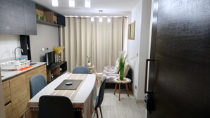 A compact kitchen with a dining area, a refrigerator, and a window with curtains. - Alojamiento en San Diego 376 (Santiago)