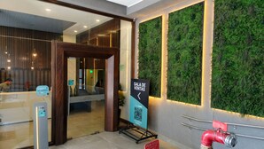 A reception area with a wooden door, a glass partition, a green wall with a QR code, and a red fire extinguisher. - Alojamiento en San Diego 376 (Santiago)