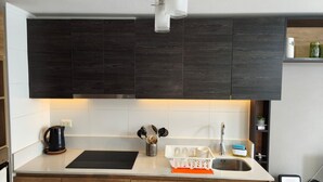 A modern kitchen with dark wood cabinets, a black countertop, and a stainless steel sink. - Alojamiento en San Diego 376 (Santiago)