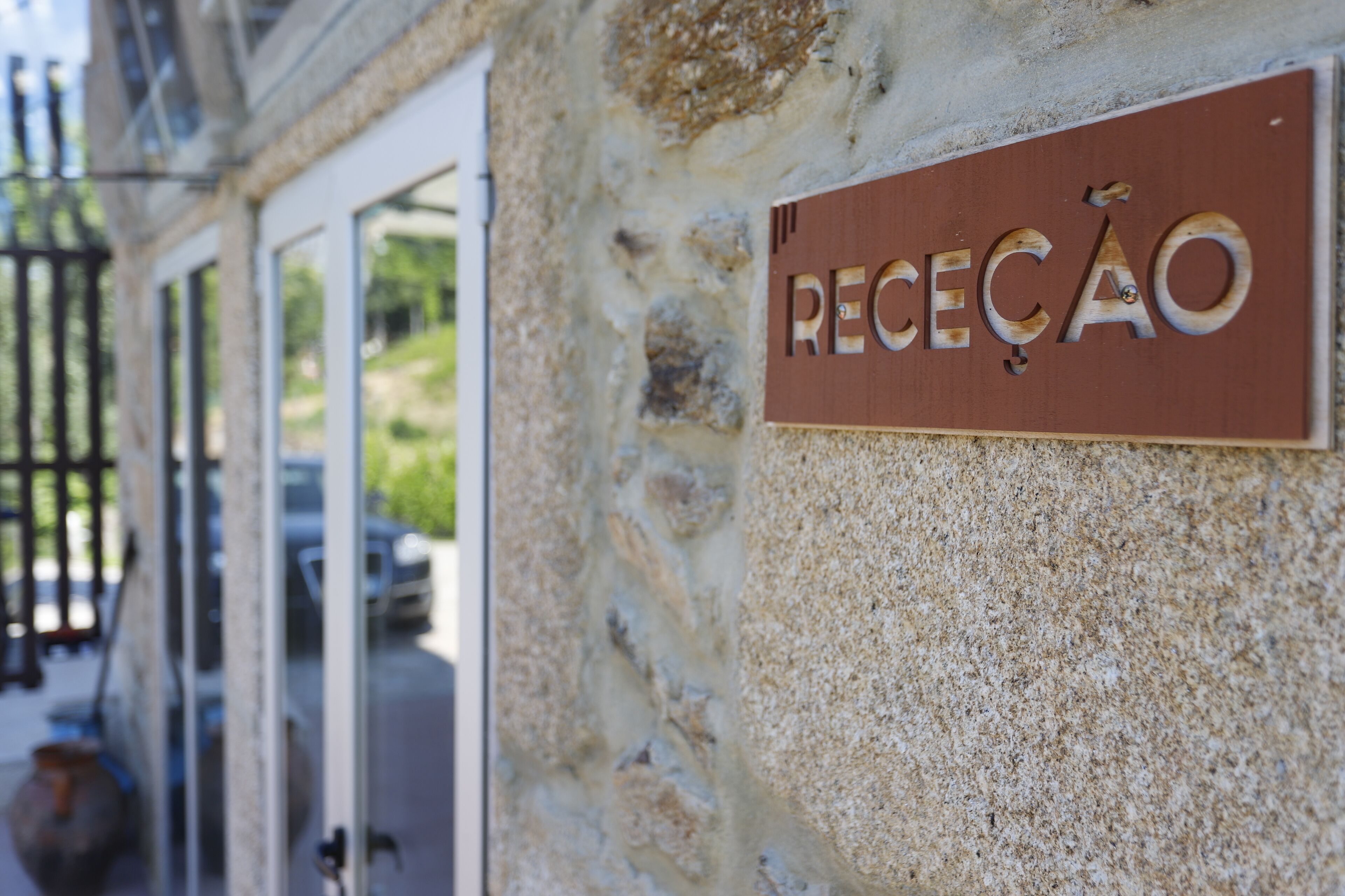 A stone wall with a sign that reads "RECEÇÃO".