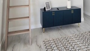 A room with a TV mounted on the wall, a dark blue cabinet below it, a wooden ladder, and a patterned rug on the floor. - New, full Casita in North Phoenix with AC, WiFi (Phoenix)