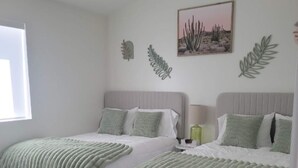 A bedroom with two beds, a ceiling fan, a window, and wall art. - New, full Casita in North Phoenix with AC, WiFi (Phoenix)