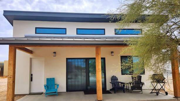 A modern two-story house with a covered porch, a sliding glass door, and a small patio area with outdoor seating. - New, full Casita in North Phoenix with AC, WiFi (Phoenix)