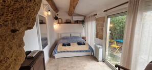 A bedroom with a bed, a radiator, a window, and a view of the outside.