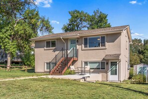 A two-story house with a front porch, a staircase, and a small patio area. - Monthly Lease Available - Mountain Views, Modern Comfort: Your Cozy Getaway (Colorado Springs)