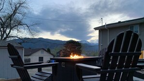 Un patio con dos sillas Adirondack, una chimenea y vistas a montañas.