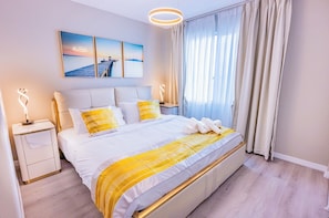 A modern hotel room with a large bed, a bedside table, a nightstand, and a view of the sea through the window. - Brand new high-end finely decorated single-family villa 5 bedrooms 6King bed 17 (Las Vegas)