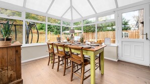 A conservatory with a wooden table set for dining, large windows, and a view of the garden. - Little Hawkcliffe Retreat | Hot Tub & Parking (West Yorkshire)