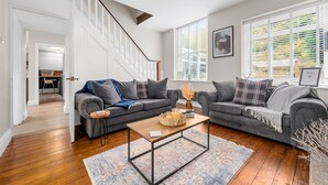 A modern living room with two grey sofas, a wooden coffee table, and a staircase leading to an upper floor. - Little Hawkcliffe Retreat | Hot Tub & Parking (West Yorkshire)