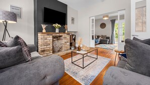 A modern living room with a fireplace, grey sofas, a coffee table, and a flat-screen TV mounted on the wall. - Little Hawkcliffe Retreat | Hot Tub & Parking (West Yorkshire)