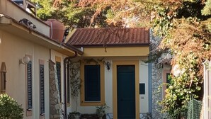 A courtyard with a gravel path leading to a building with a tiled roof and a dark door.