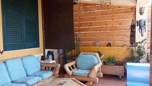 A cozy outdoor seating area with a sofa and chairs, a small table, and a decorative wall with wooden slats and wall art.