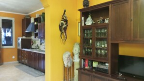 A living room with a TV, wooden cabinets, and a glass cabinet with decorative items.