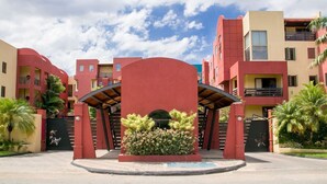 A hotel entrance with a red archway, a central garden, and multiple balconies. - CTBH @ Argyle #3 [1-Bedroom w/ Pool] (Kingston)