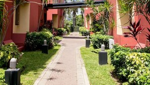 A pathway leading to a building with a red facade and a pedestrian bridge. - CTBH @ Argyle #3 [1-Bedroom w/ Pool] (Kingston)