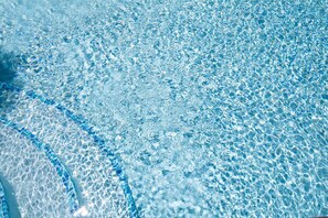 A clear view of a swimming pool's edge with a tiled pattern.