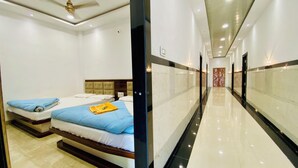 A hotel corridor with two beds, a ceiling fan, and a marble floor. - Hotel Radhe Shree (Khandwa)