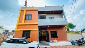 A two-story building with a red brick facade and a yellow accent wall. - Hotel Radhe Shree (Khandwa)