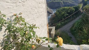 Un balcone con un muro bianco, una ringhiera in metallo e vista su un paesaggio montuoso.