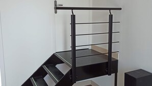 Eine Treppe mit schwarzer Handlauf und Metallspindeln, die zu einer weißen Tür führt.