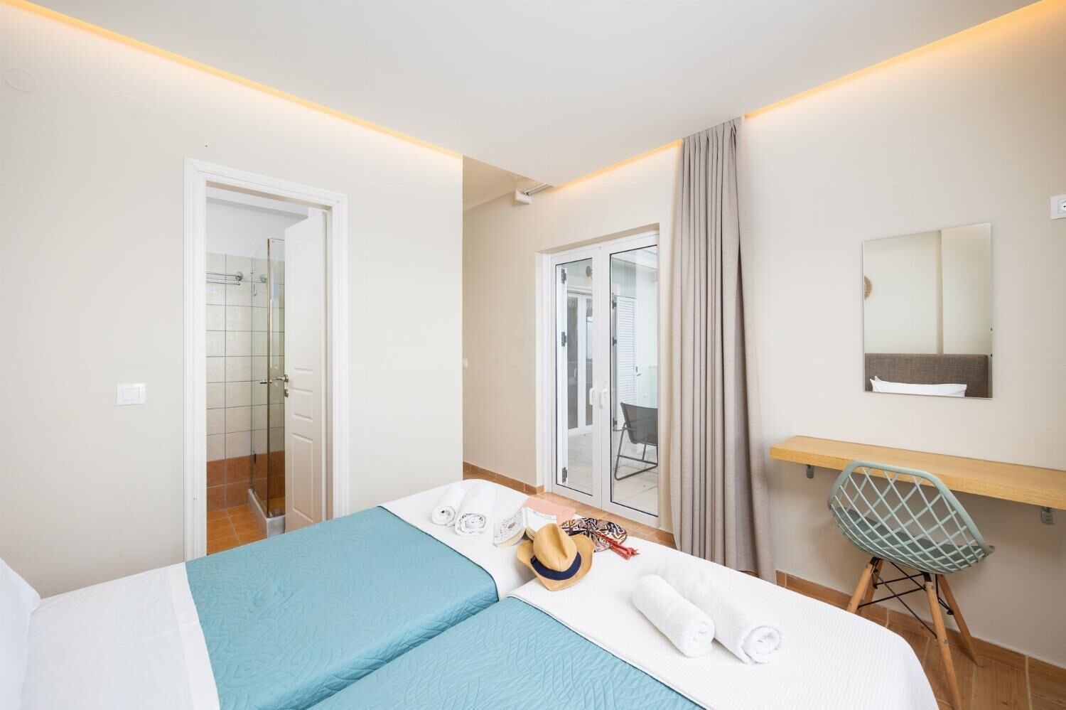 A hotel room with a bed, a desk, a chair, a shower, and a balcony with a view.