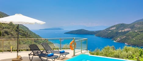 Un espace piscine offrant une vue dégagée sur la mer et les collines.