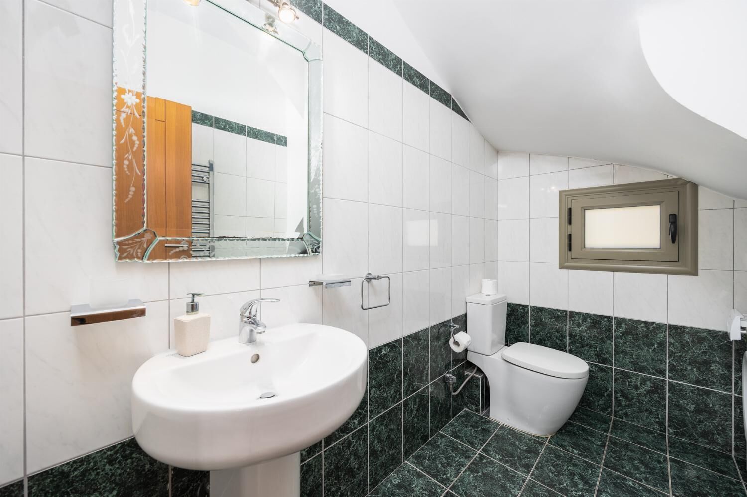 A bathroom with a white sink, a toilet, and a mirror.