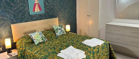 A bedroom with a bed, nightstands, a dresser, and a mirror.