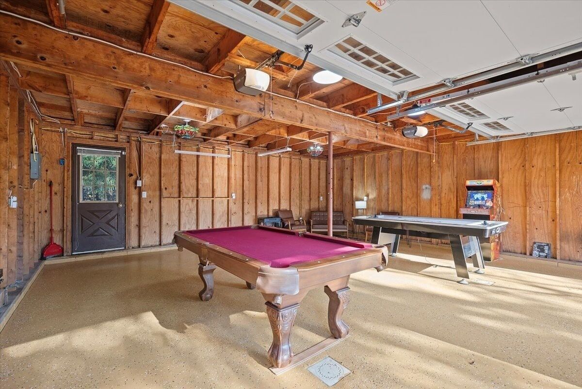 Un intérieur en bois avec une table de billard, une porte et une table entourée de chaises.