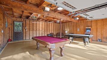 Un intérieur en bois avec une table de billard, une porte et une table entourée de chaises.