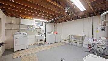 Une buanderie équipée d’un lave-linge, d’un sèche-linge et d’une table à repasser.