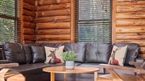 Ein Holzblockhaus-Innenraum mit Ledersofa, Holztisch und Topfpflanze.