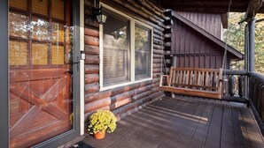 Eine Blockhütte mit einer Holzterrasse, einer Bank und einem Blumentopf.